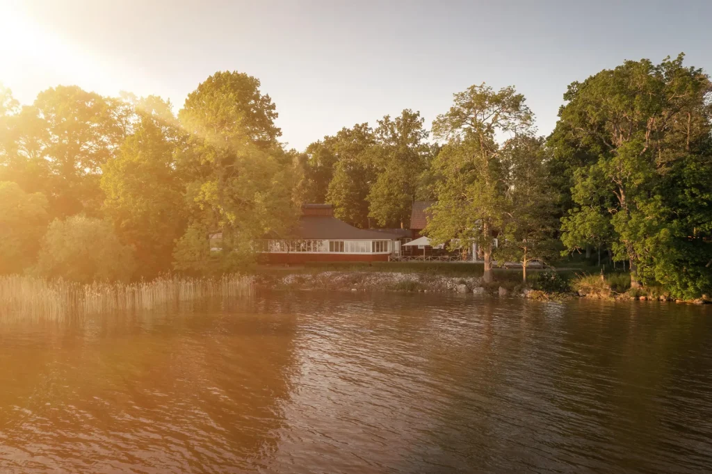 Ett rött hus vid en sjö inbäddat av gröna träd.