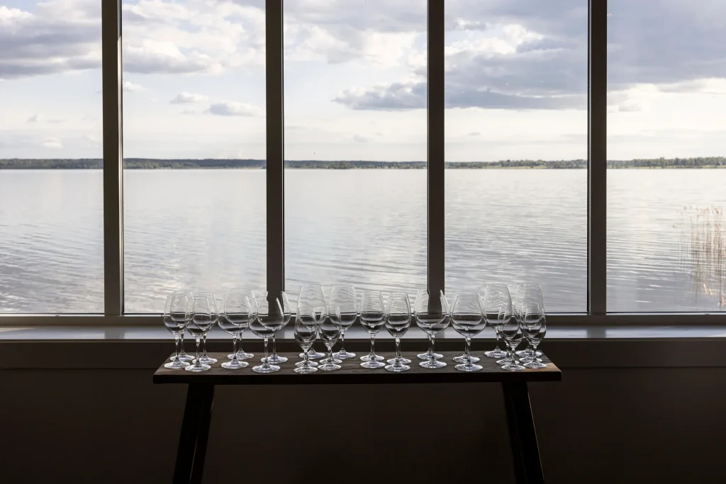 Ett bord med vinglas framför ett fönster med utsikt över en sjö.